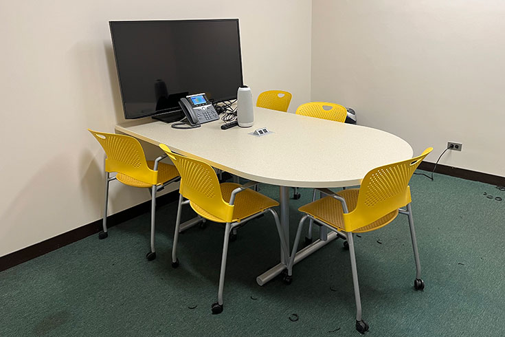 A table, television, and chairs in a small room