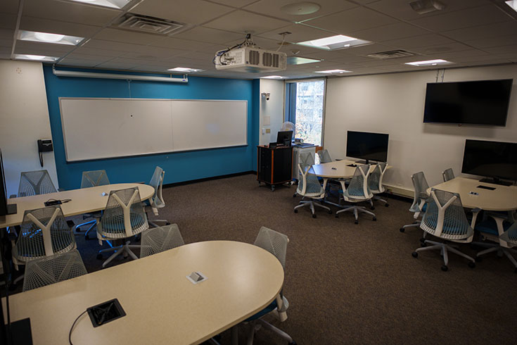 A large room with multiple tables and desk chairs