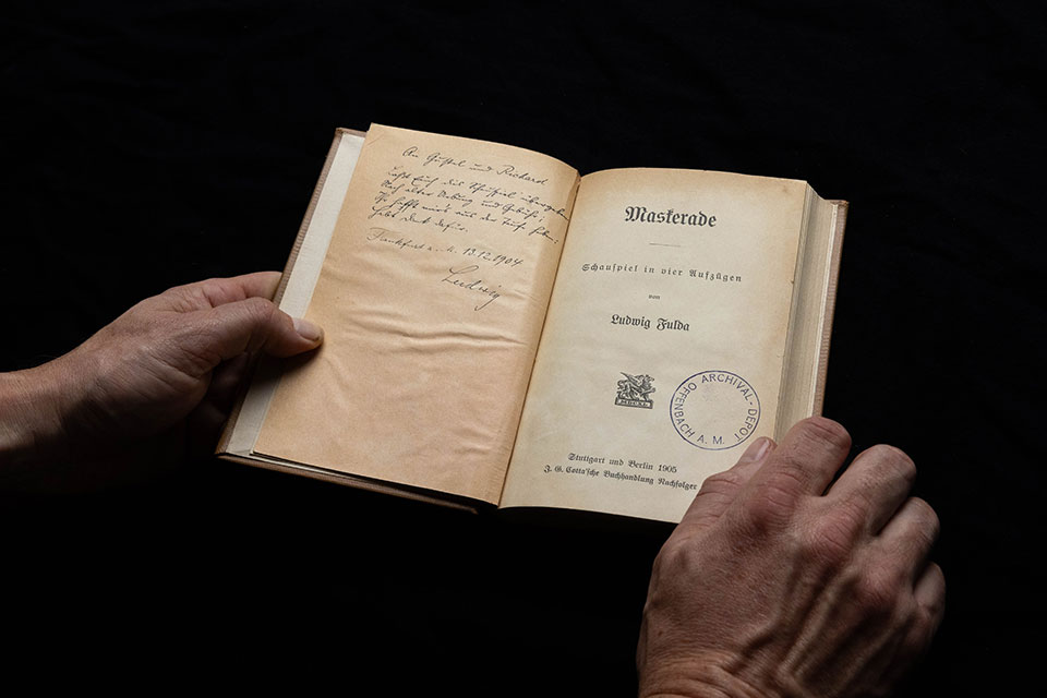 Hands holding a book with a stamp on the cover page.