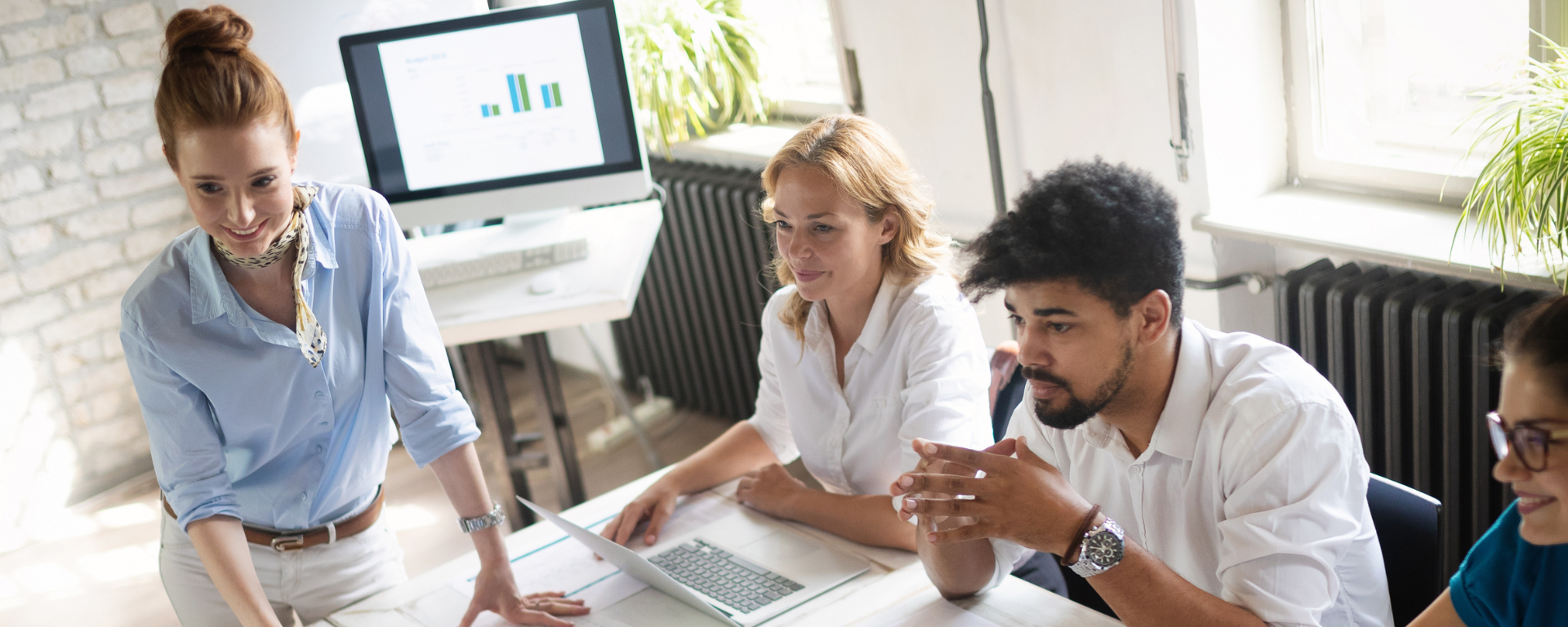 Colleagues sit at a conference table, smiling as they review charts