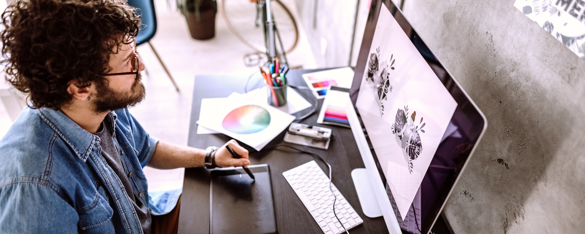 Person working at a desktop, using a electronic pad and pen to draw on the screen.