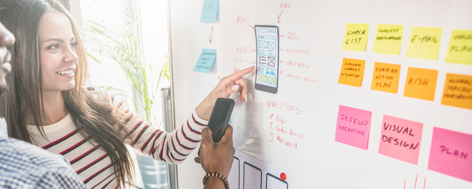 Two people pointing at a prototype on a white board