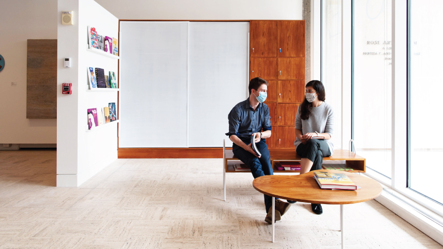 Two visitors sit in the Rose's lobby reading catalogs