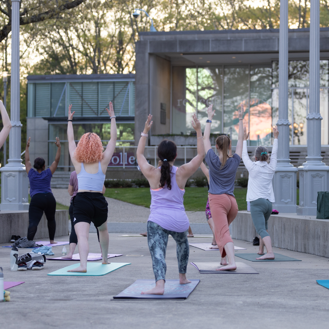 A young woman stretches in a yoga pose outside the Rose Art Museum