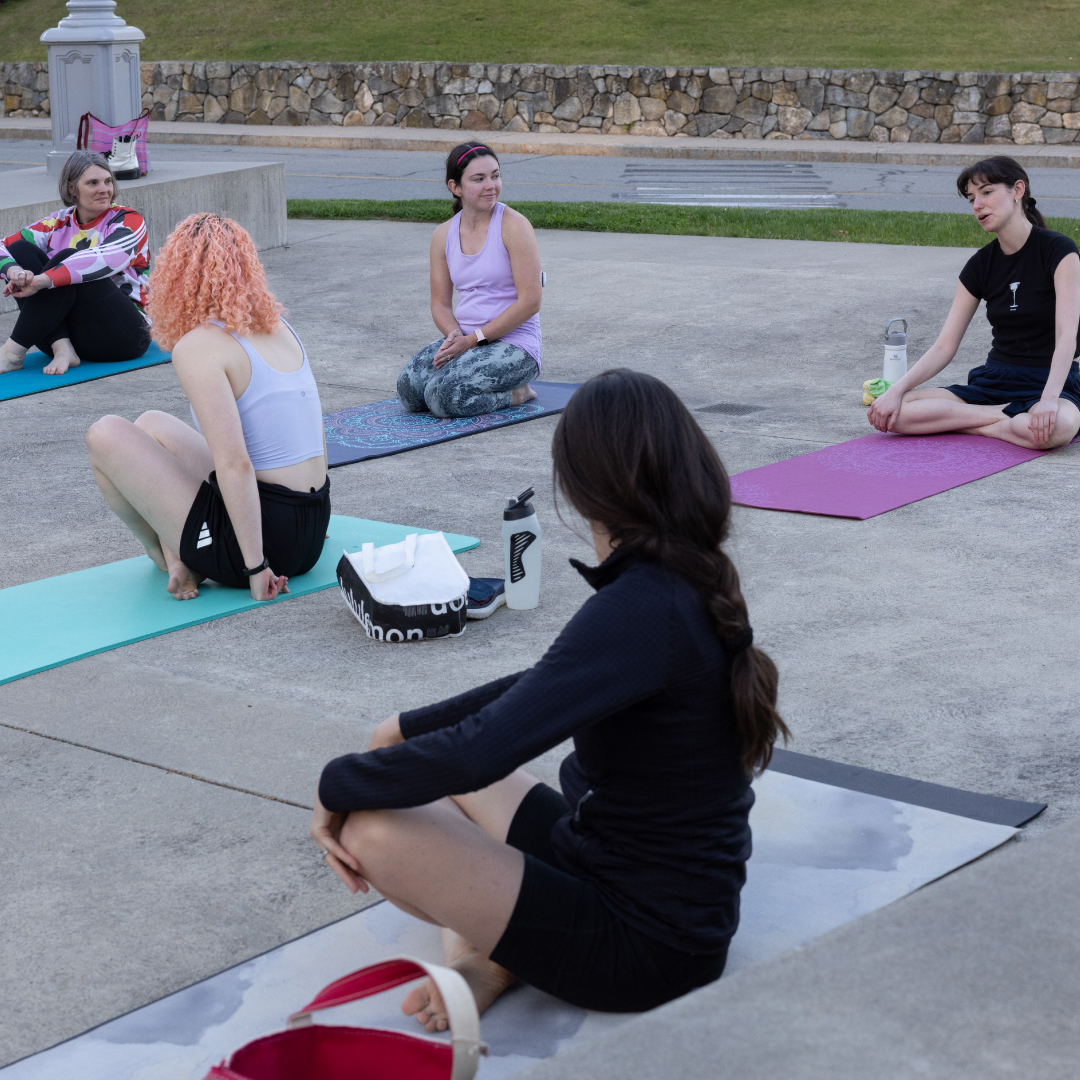 A young woman stretches in a yoga pose outside the Rose Art Museum